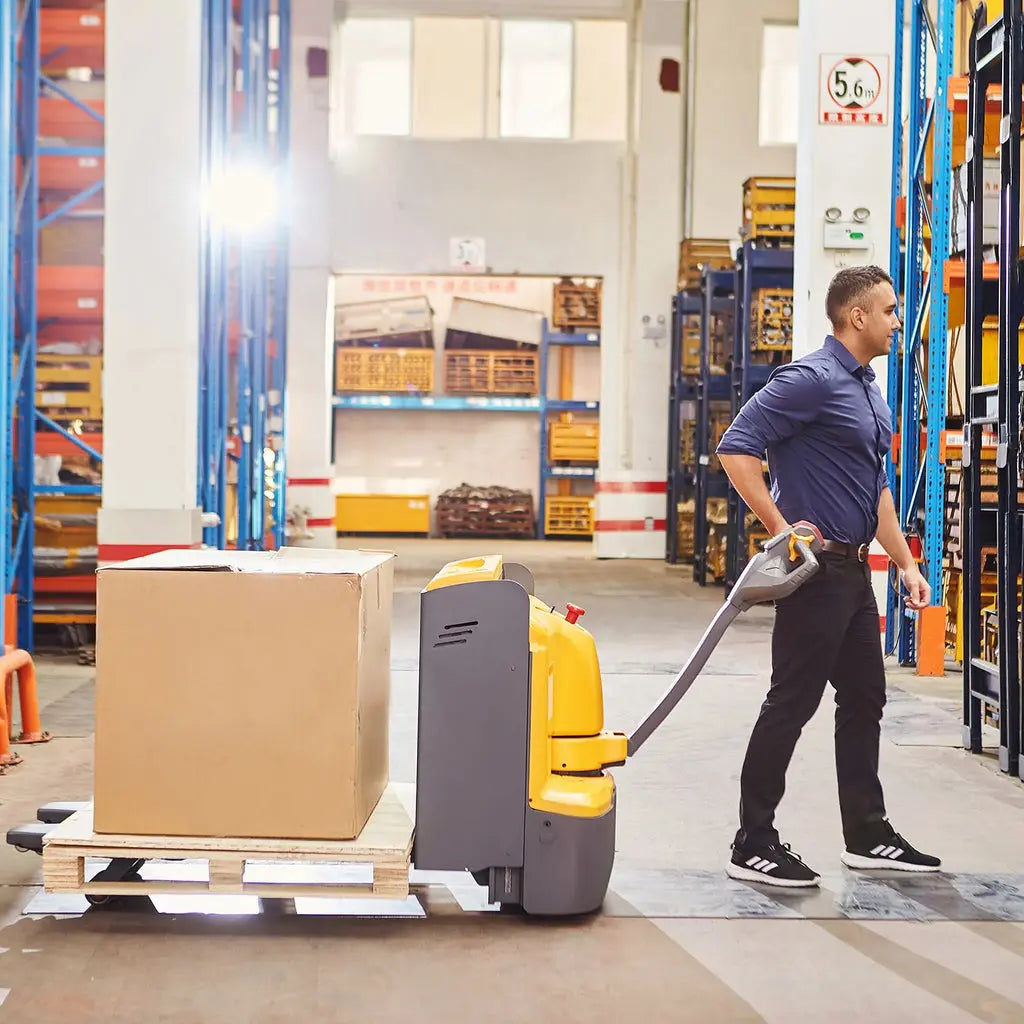 Apollolift A-1023 electric pallet jack moving a loaded pallet in a warehouse with a worker operating it