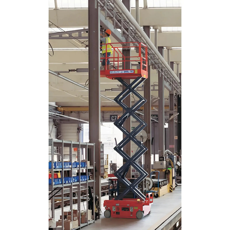 Ballymore drivable compact scissor lift elevated in an industrial warehouse with worker on platform
