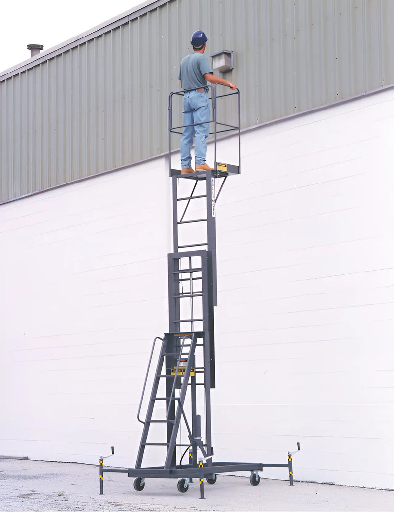 Person working on elevated black platform with safety rails and wheels.
