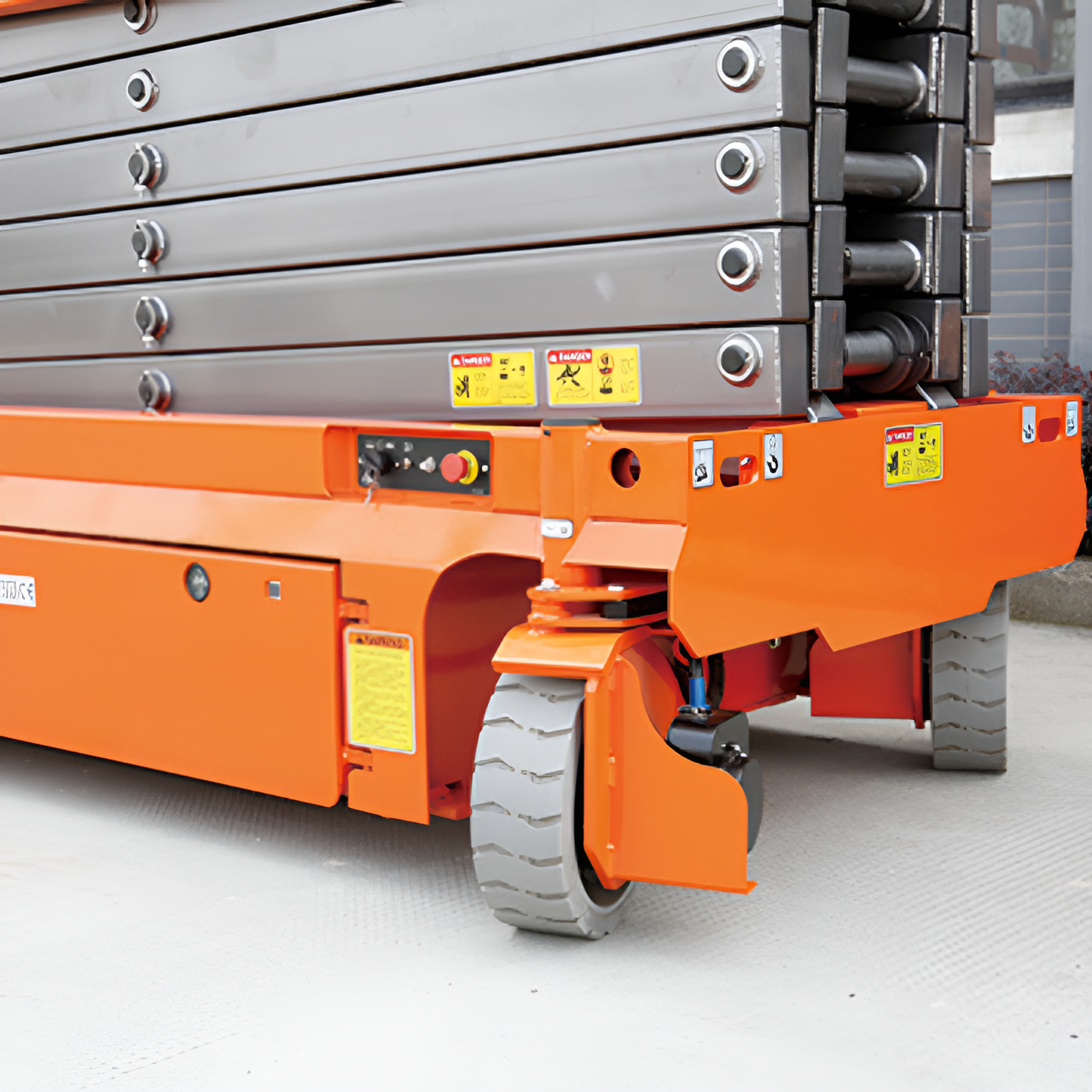 Close-up view of orange scissor lift base and heavy-duty wheels.