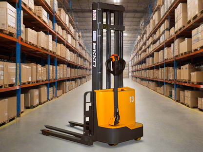 Orange and black electric stacker forklift in warehouse with tall shelves.