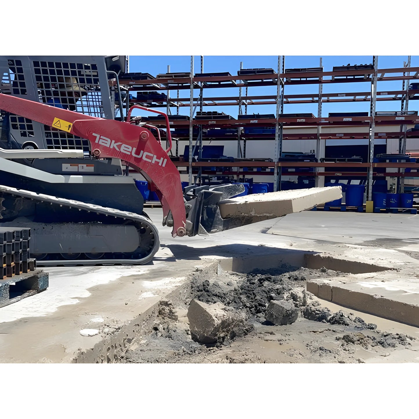 Takeuchi mini excavator lifting concrete slab at construction site with Star Industries 127