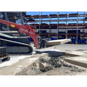 Takeuchi mini excavator lifting concrete slab at construction site with Star Industries 127