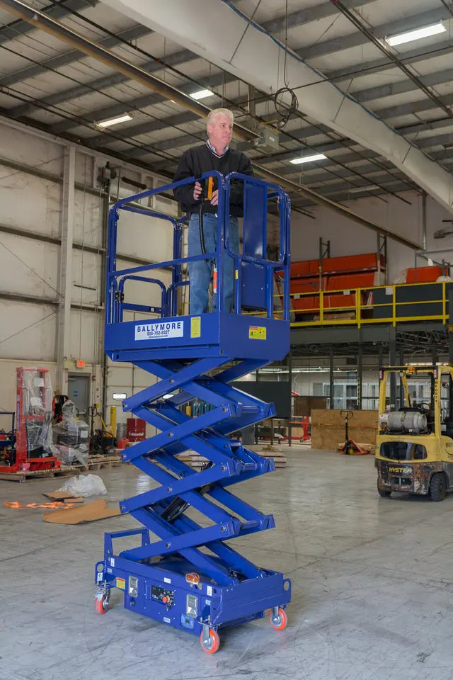 Ballymore blue compact scissor lift with man operating inside indoor warehouse setting
