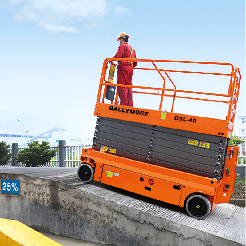 Ballymore drivable scissor lift in orange with safety rails and worker in safety gear operating outdoors