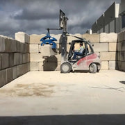 Kenco Bin Block Lift in use with a forklift for moving concrete blocks in a storage area