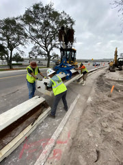 Workers using Kenco Concrete Barrier Lift to safely position concrete barriers on a construction site