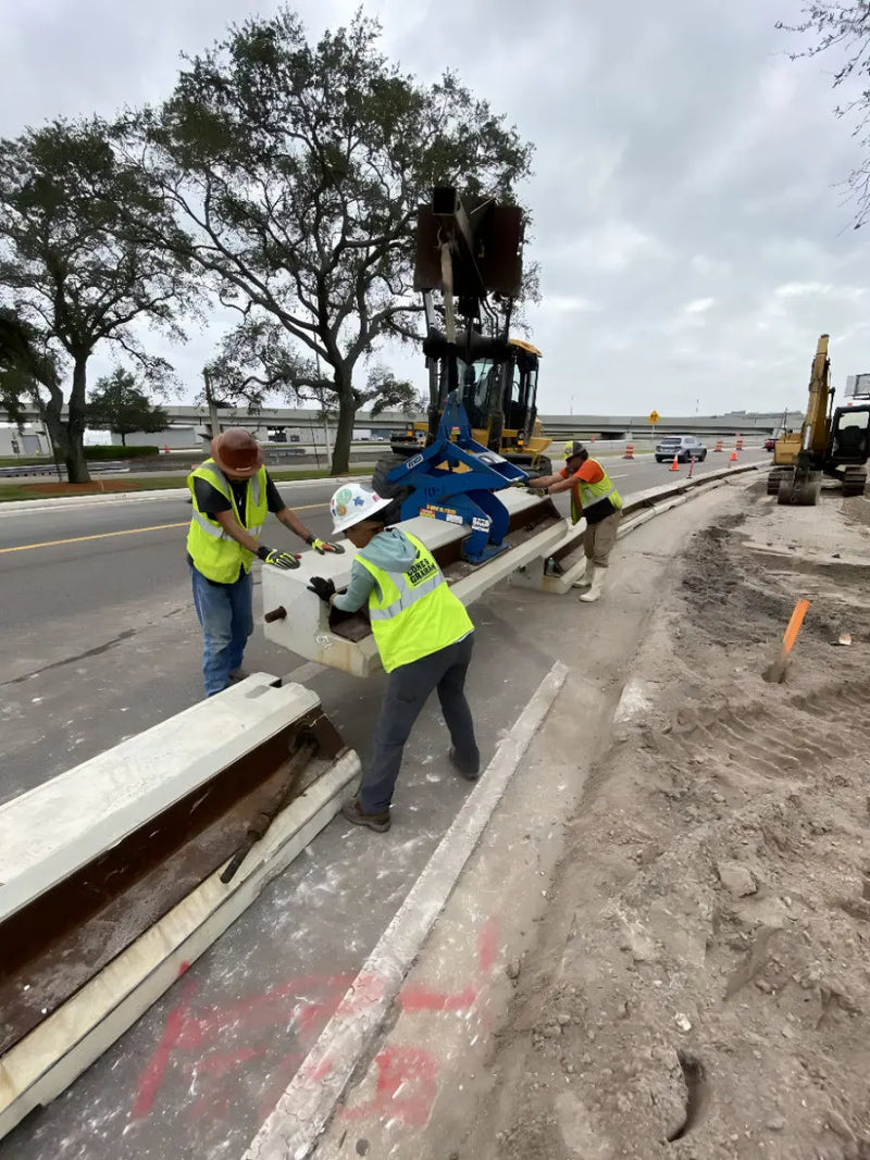 Workers using Kenco Concrete Barrier Lift to safely position concrete barriers on a construction site