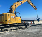 Kenco Concrete Barrier Lift attached to a CAT excavator lifting concrete barriers on a construction site
