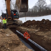 Kenco Concrete Pipe-Lift in use with excavator lifting concrete pipe from a trench at a construction site