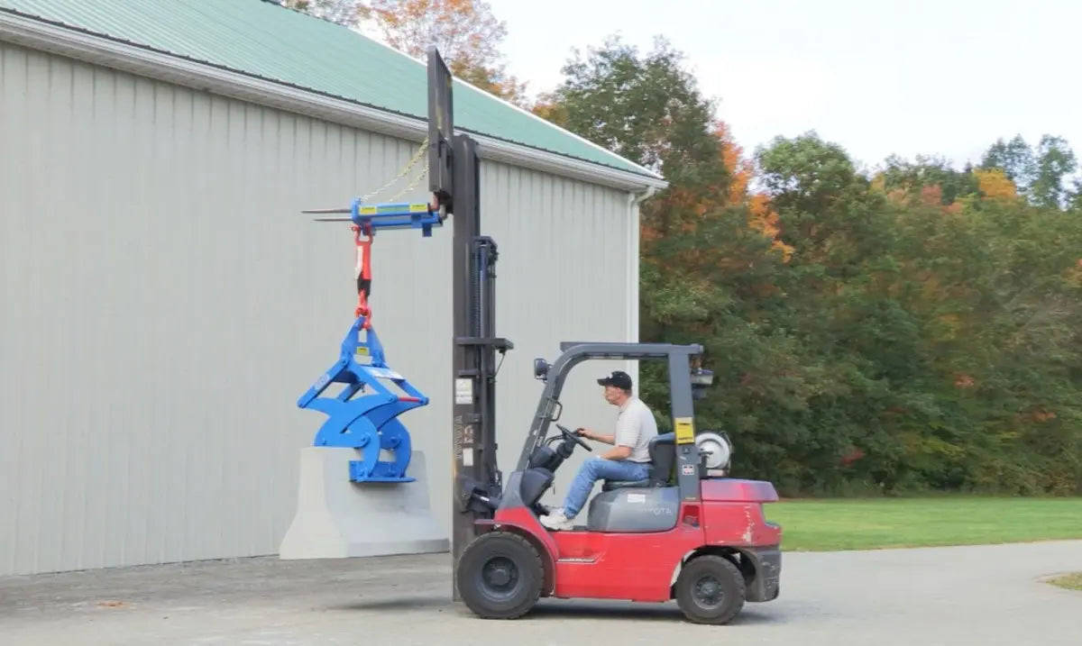Kenco Forklift Adapter attached to a forklift, lifting a large concrete block outdoors