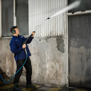 Worker using Makinex DPW-4000-0A-VU-50 pressure washer to clean a wall with protective ear muffs