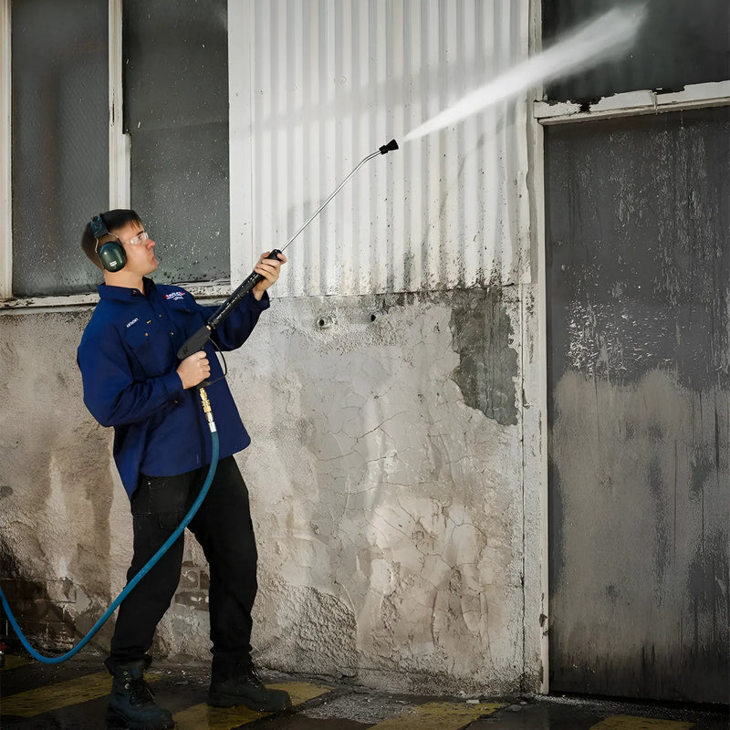 Worker using Makinex DPW-4000-0A-VU-50 pressure washer to clean a wall with protective ear muffs