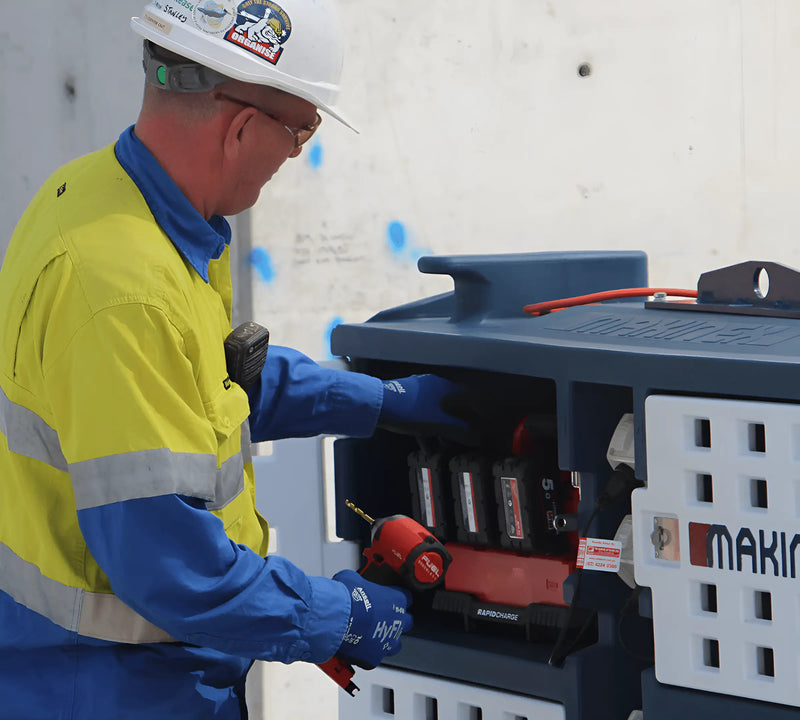 A worker using the Makinex Mobile Charge Pod to charge power tools on a construction site