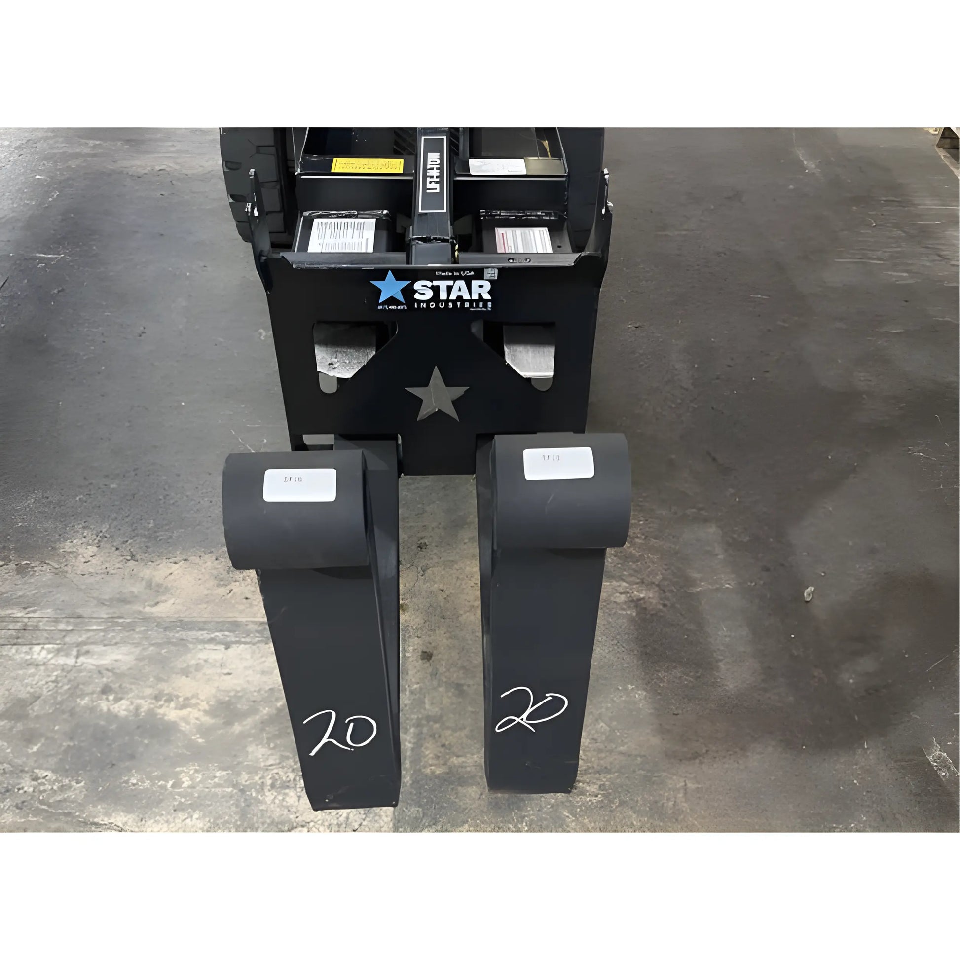Star Industries 1390-FM forklift fork extensions placed on a warehouse floor in front of a forklift