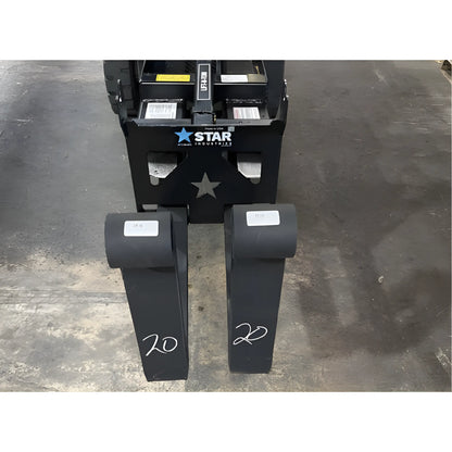 Star Industries 1390-FM forklift fork extensions placed on a warehouse floor in front of a forklift